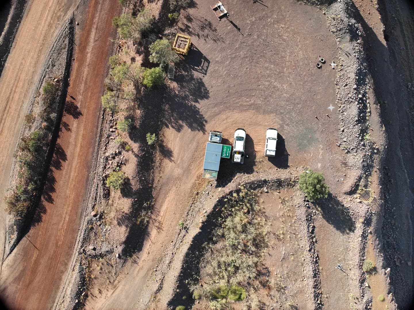 Overhead survey view of two white vehicles and cleared ground beside an Argyle haul road