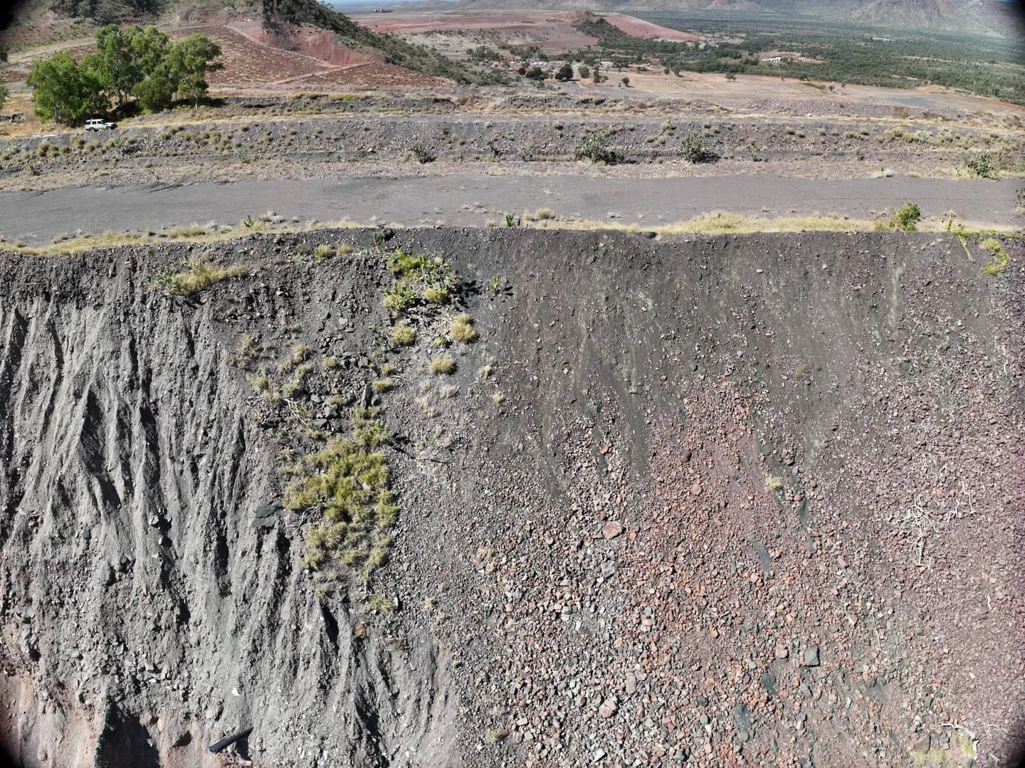 Steep exposed mine face with an access road and vegetation above at Argyle