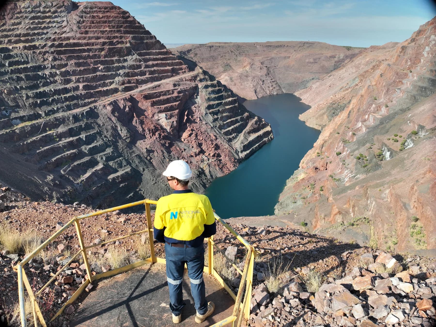 National Drones team member in a branded yellow shirt overlooking the terraced Argyle Diamond Mine pit