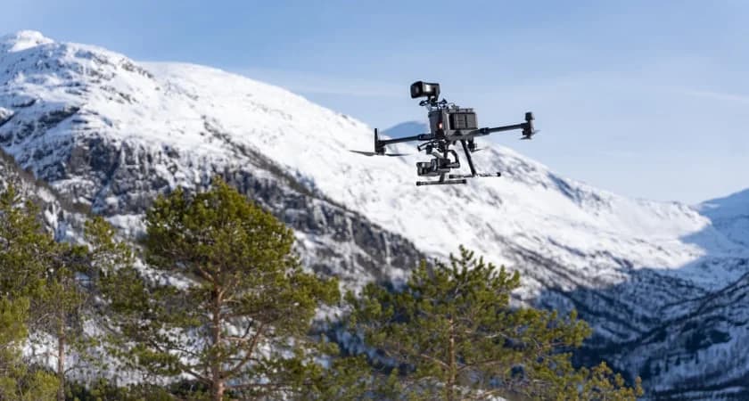 DJI Matrice 350 RTK flying in a snow-covered mountain landscape.