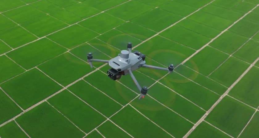 DJI Mavic 3M flying above green agricultural fields.