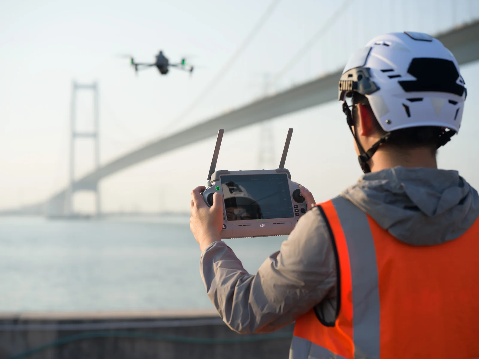 Pilot operating a Matrice 4 Series aircraft beside a bridge.