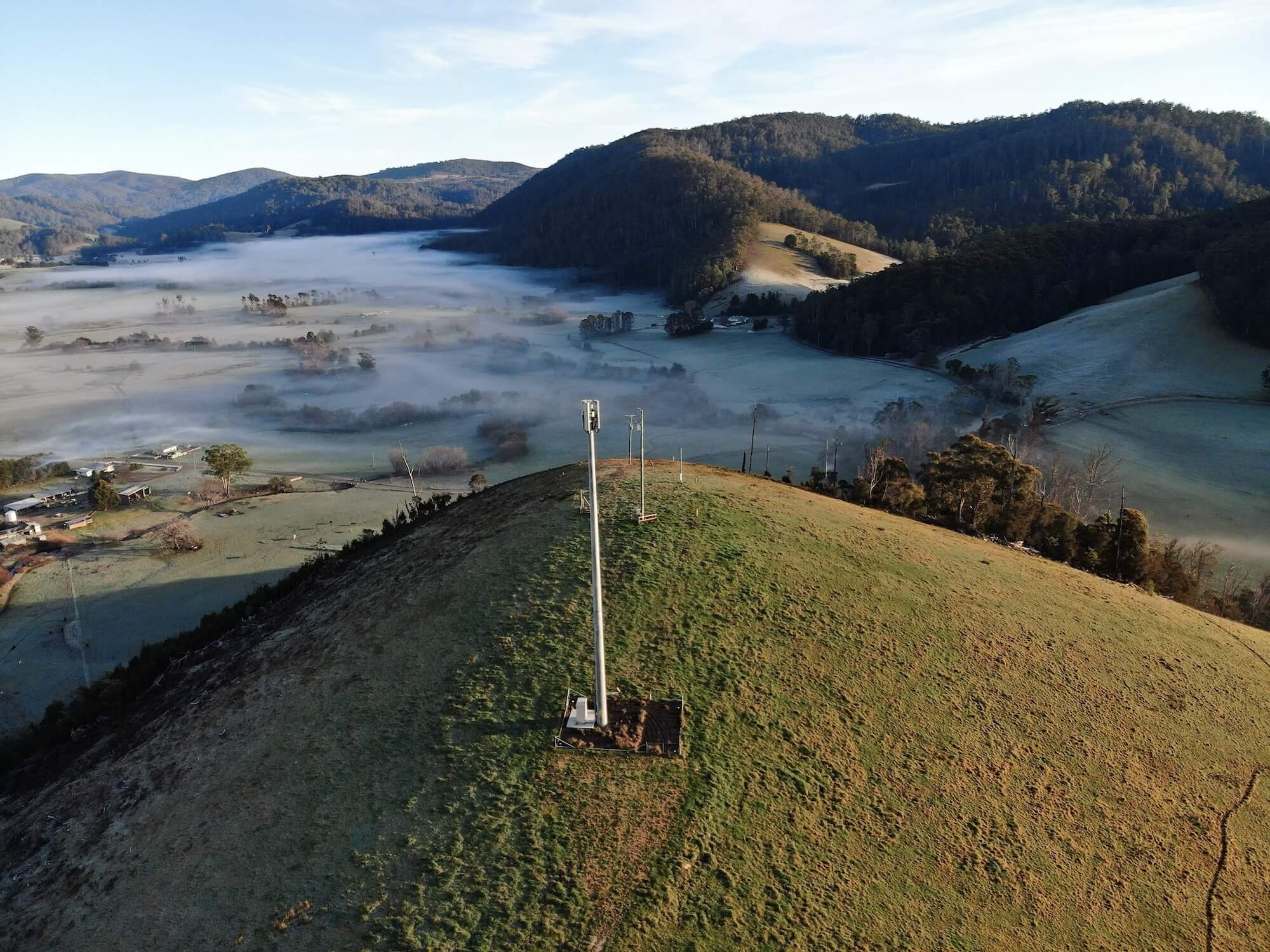 Aerial view of a communications tower in a misty mountain valley